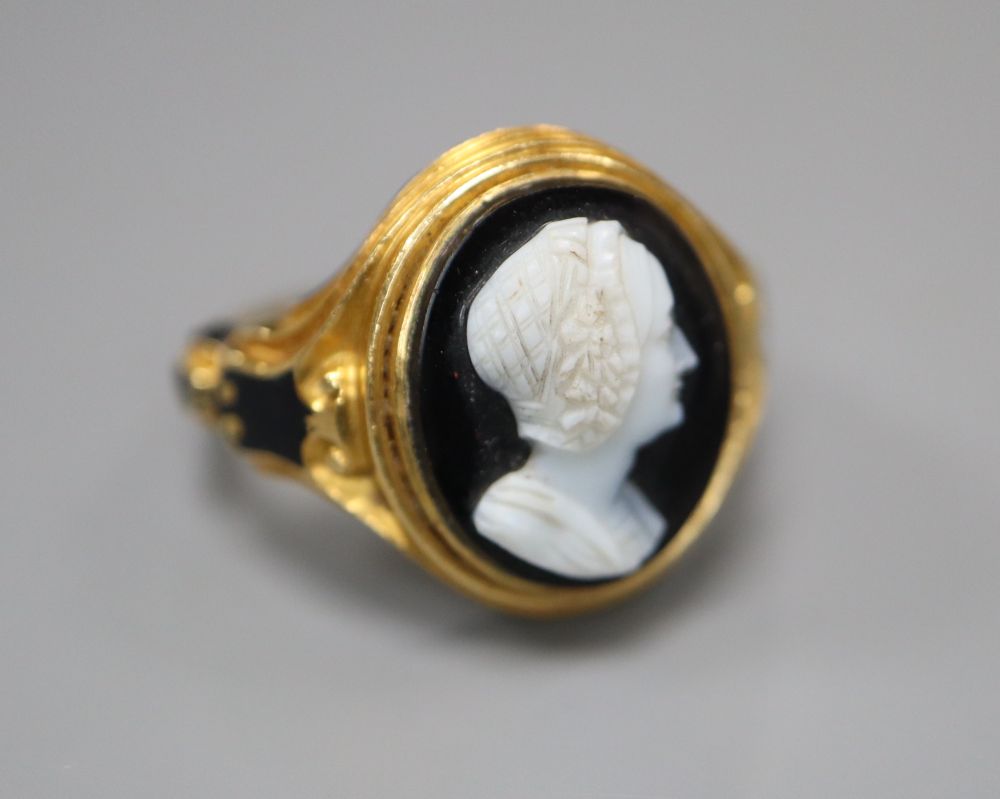 A Victorian 18ct gold cameo ring, of carved scrolled design with black enamelled decoration and hairwork panel, size M/N,